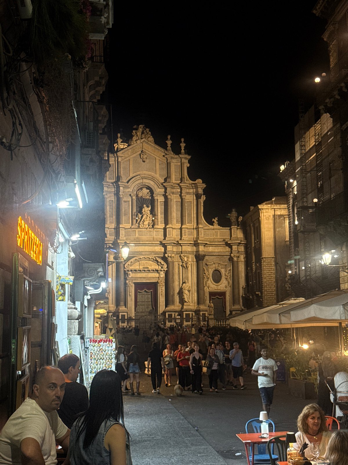 Evening street activity observed near historic Catania basilica