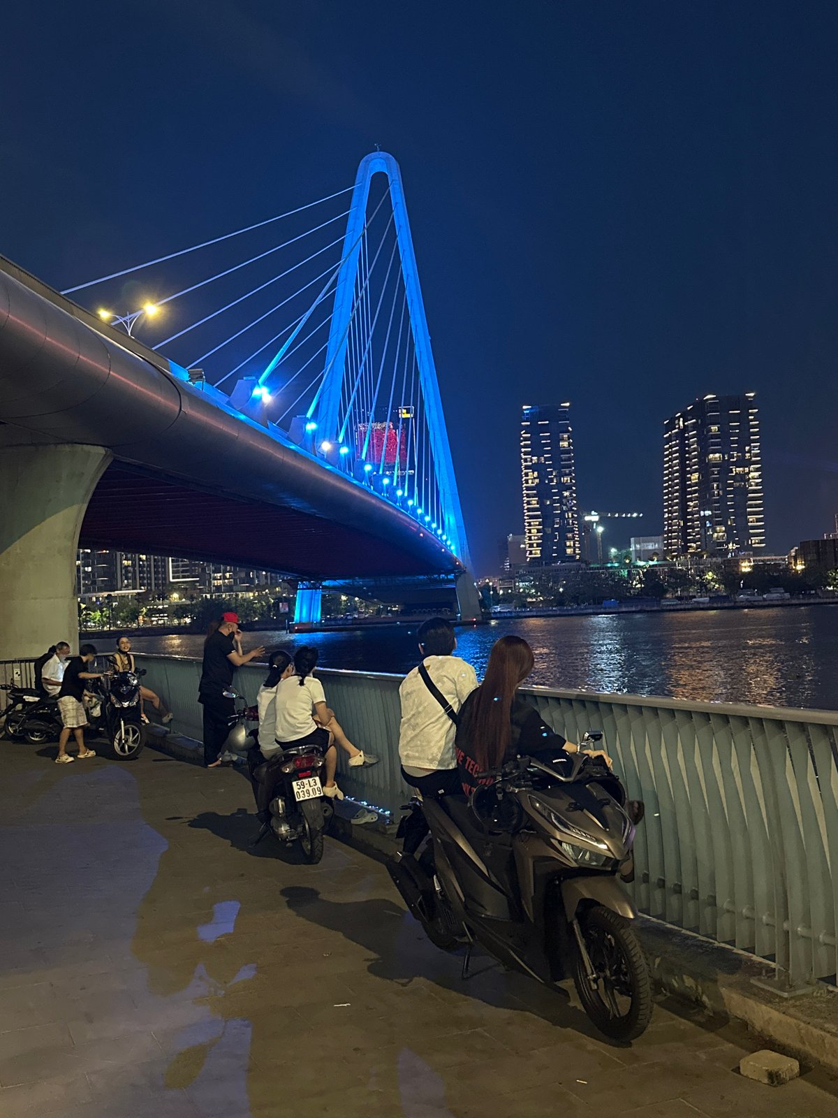 Nighttime pedestrian activity captured on illuminated Thủ Đức bridge