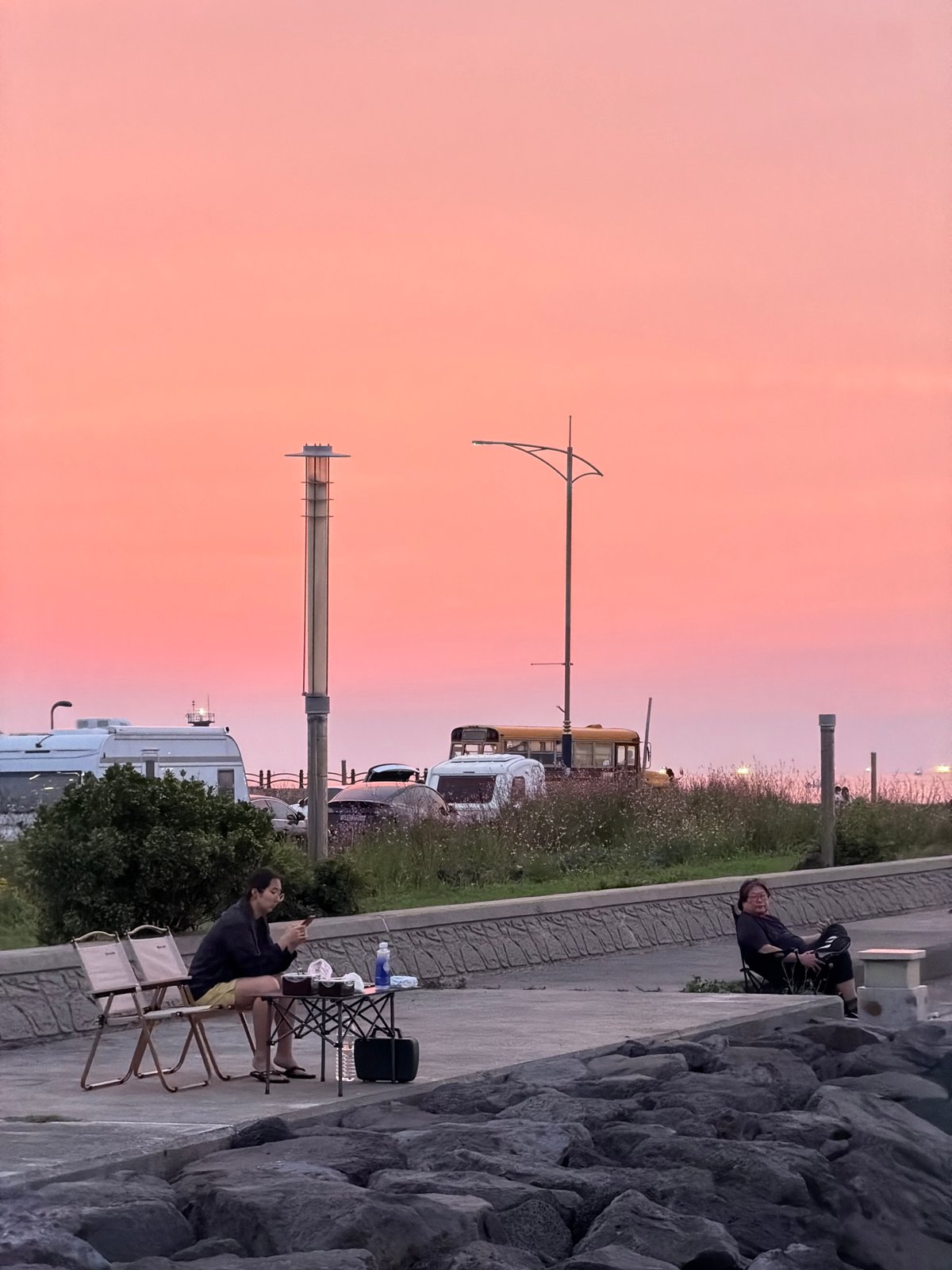 Dusk along Jeju's volcanic coastline, grill lit, sky glowing