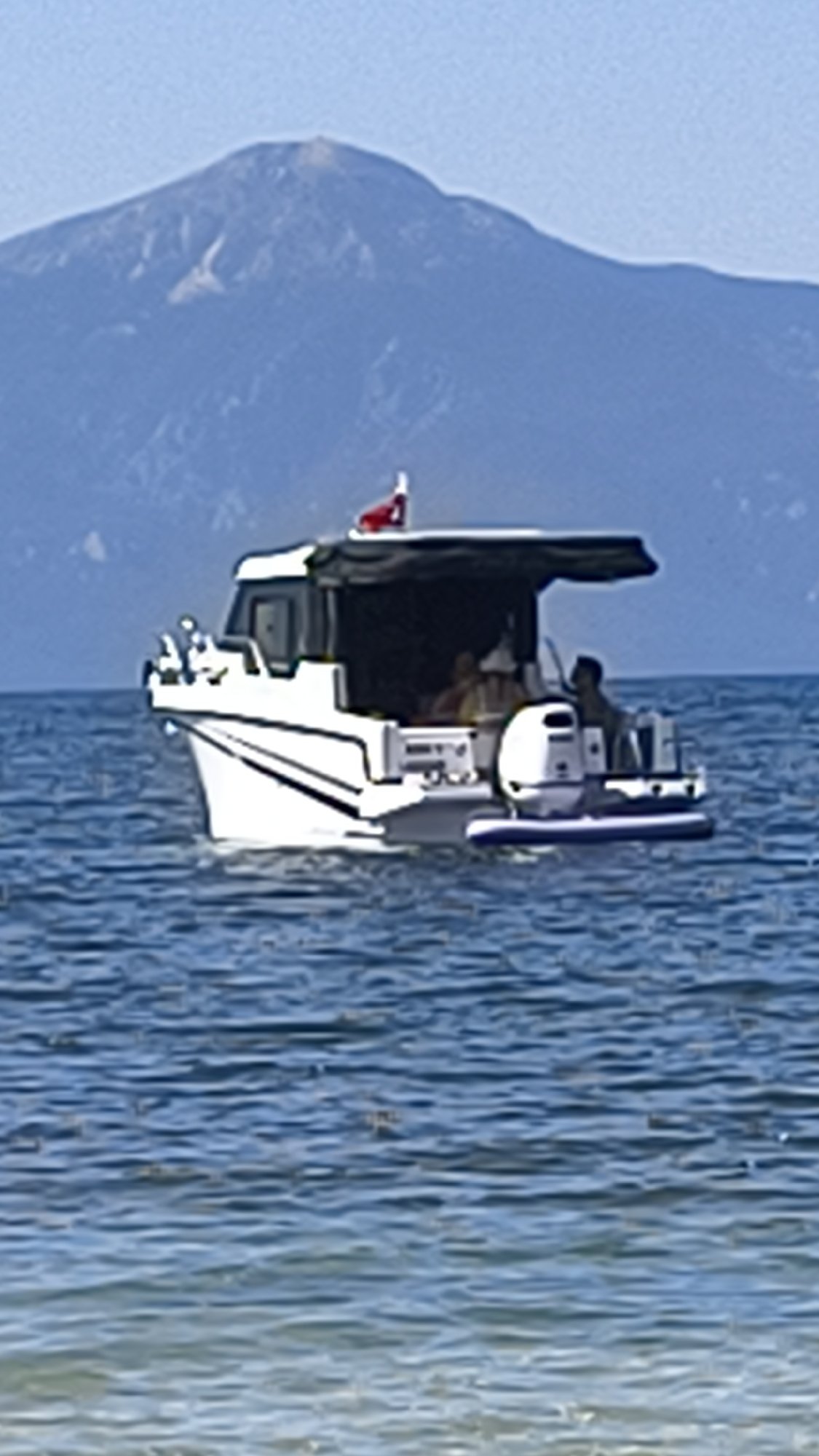 Motorboat flying Turkish flag cruises calm Aegean waters near Kuşadası