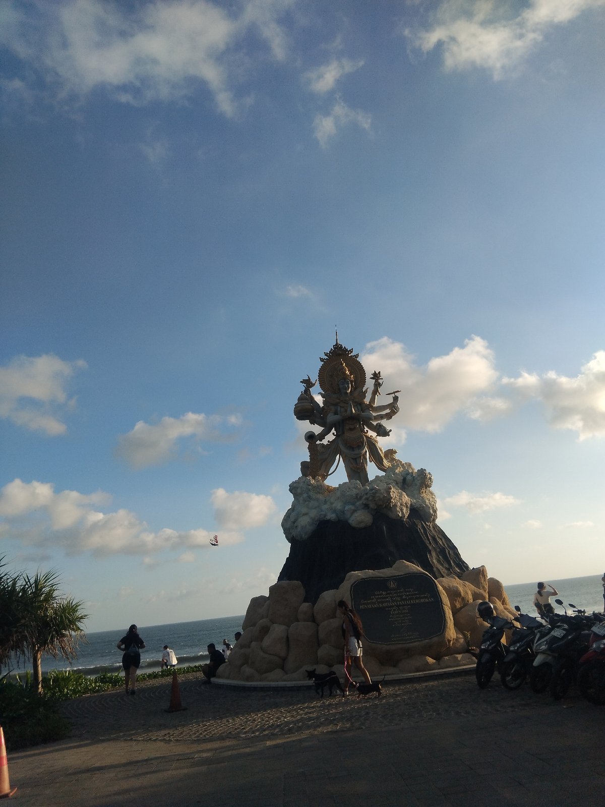 Coastal scenes documented including statue, beachgoers photographing ocean