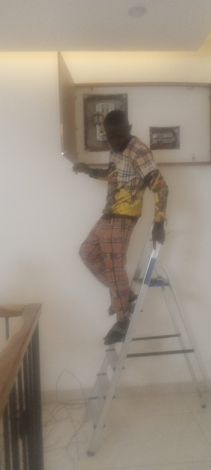 Man on ladder observed in interior space with decorative railings
