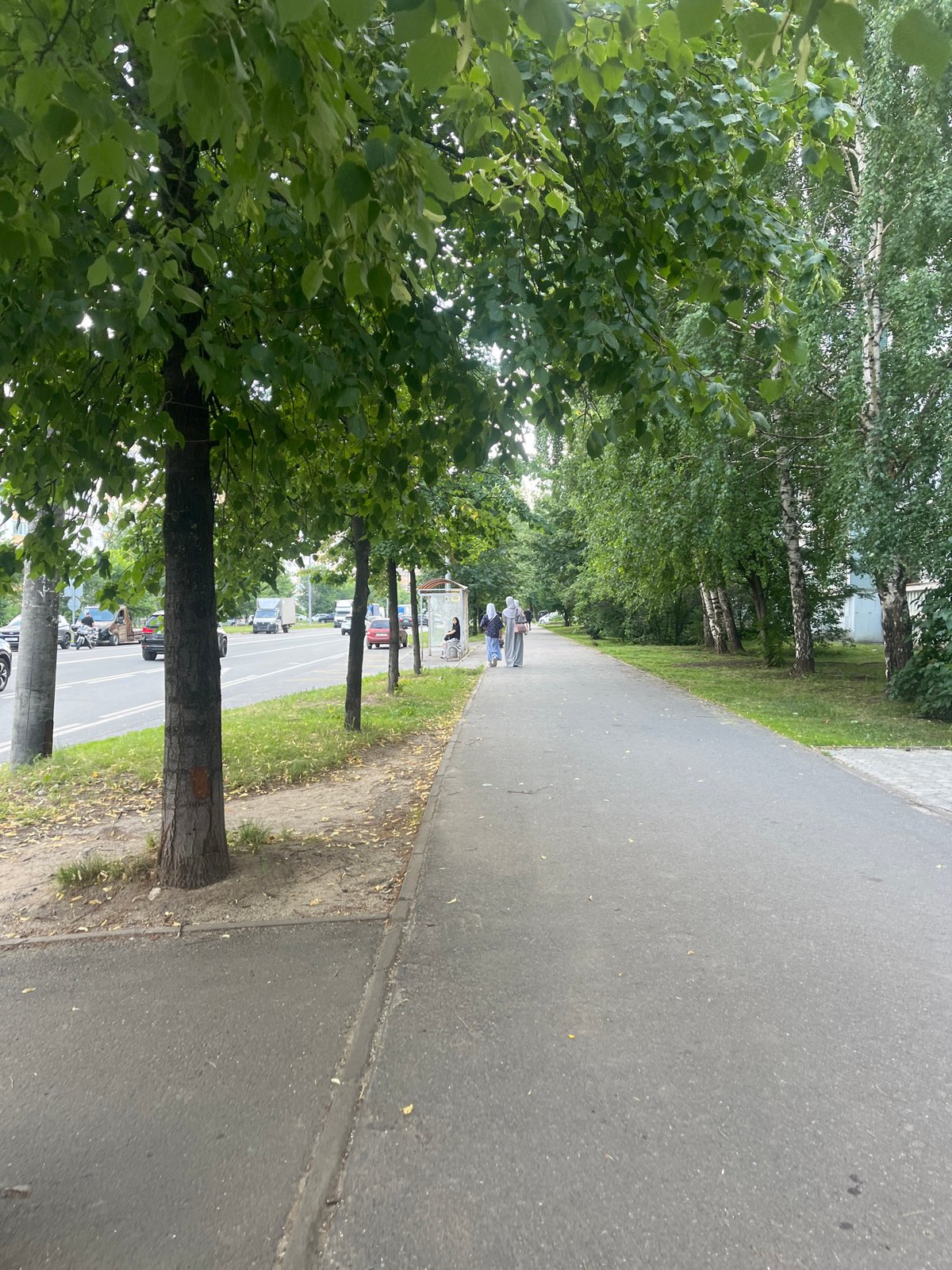 Quiet urban street scene with foot traffic, greenery, and a parked loader