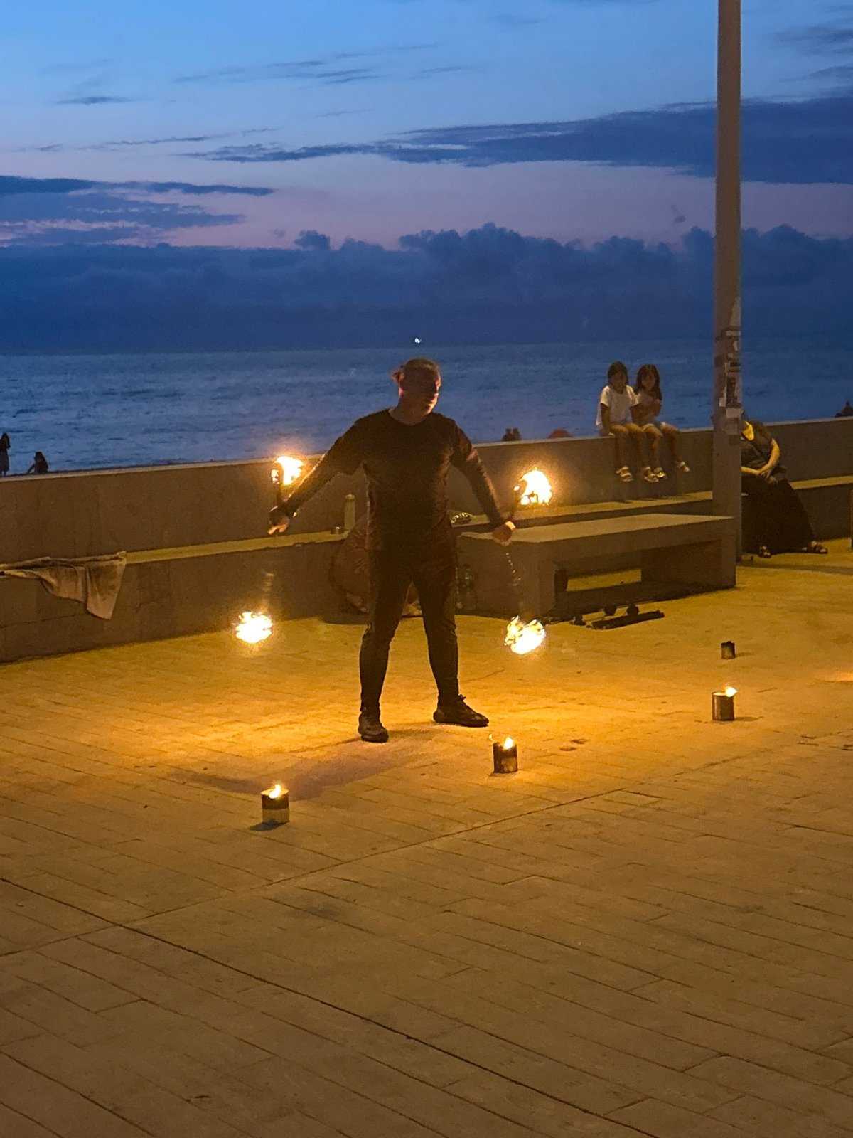 Fire performer works Batumi's waterfront promenade at dusk