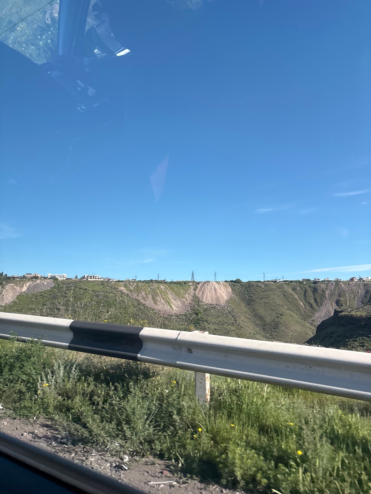 Vehicle travels mountainous road in Kanakeravan, Armenia under clear skies