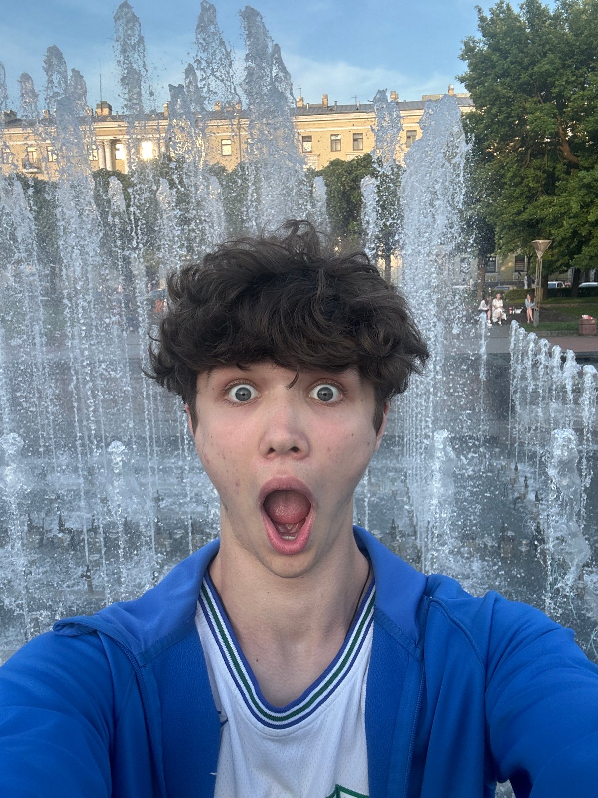 Young man takes selfies at city fountains and waterfront