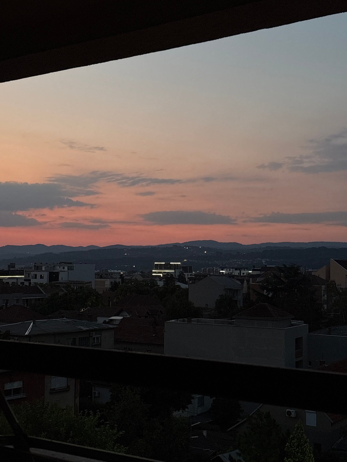 Kragujevac skyline at dusk, mountains silhouetted on the horizon