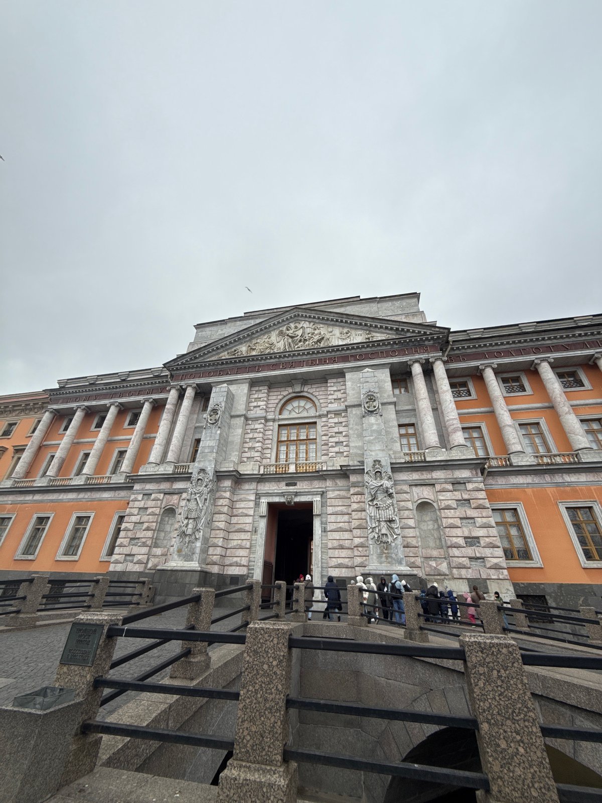 Tourist photographs historic Saint Petersburg landmarks under cloudy skies