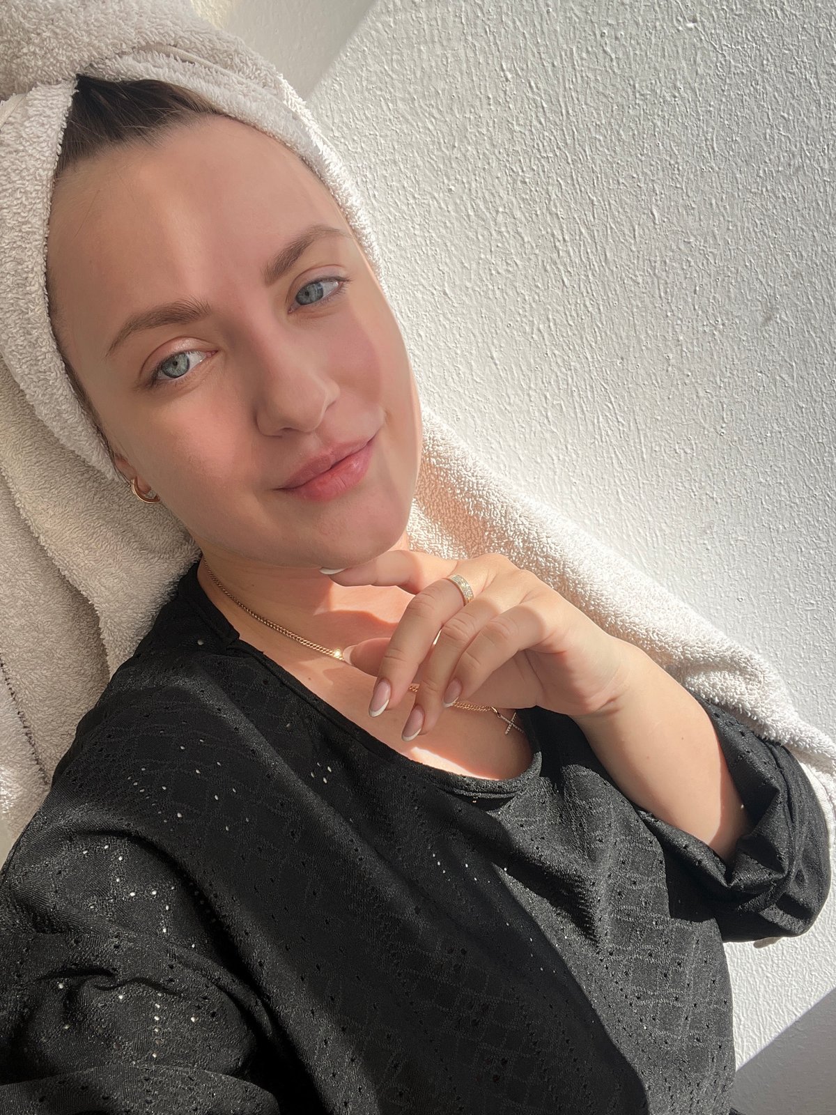 Woman rests with towel-wrapped hair in sunlit Russian interior