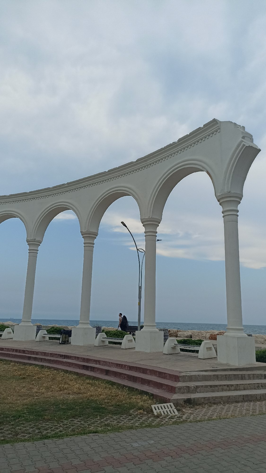 Cats claim seaside promenade in Yenişehir during overcast afternoon