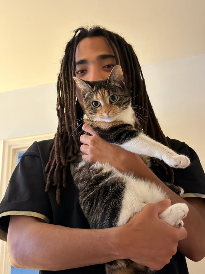 Person with dreadlocks holds mixed-color cat in Paris