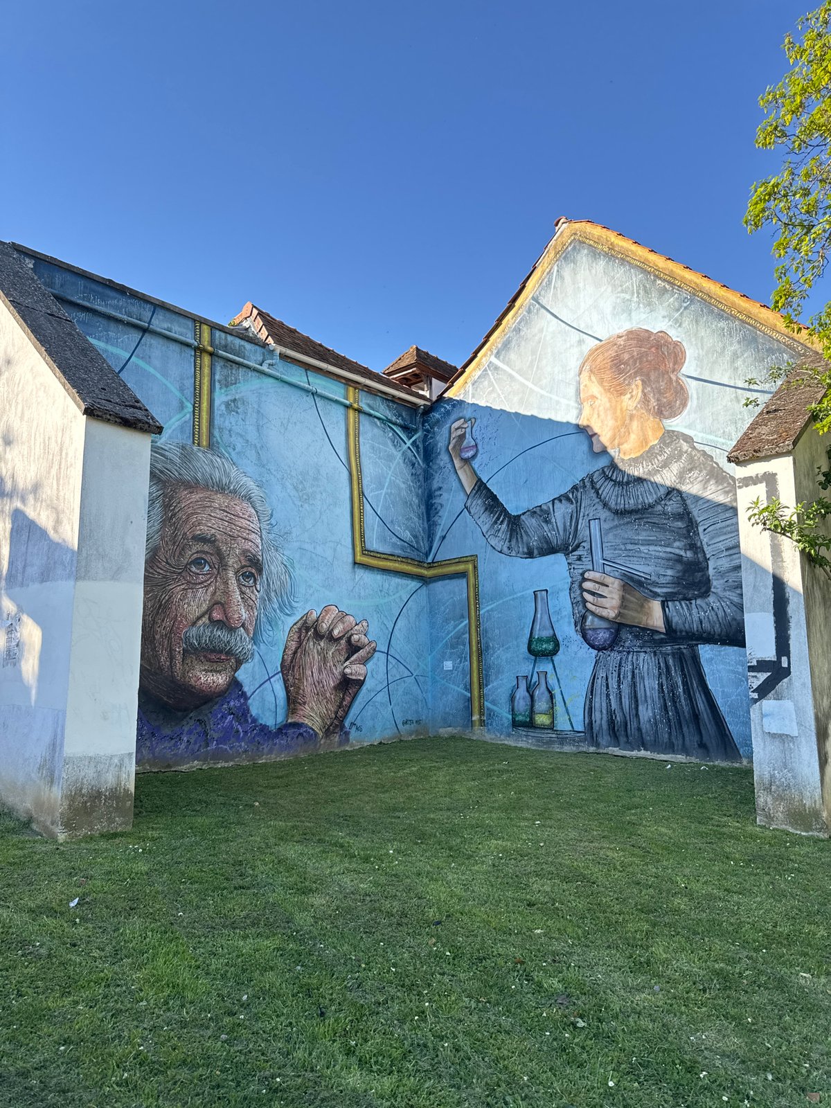 Person photographed near Curie-Einstein mural in Palaiseau, France