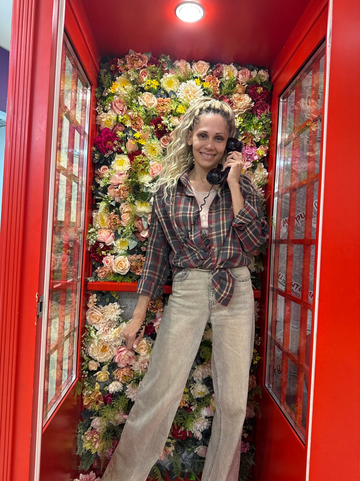 Woman poses with flowers in decorated phone booth