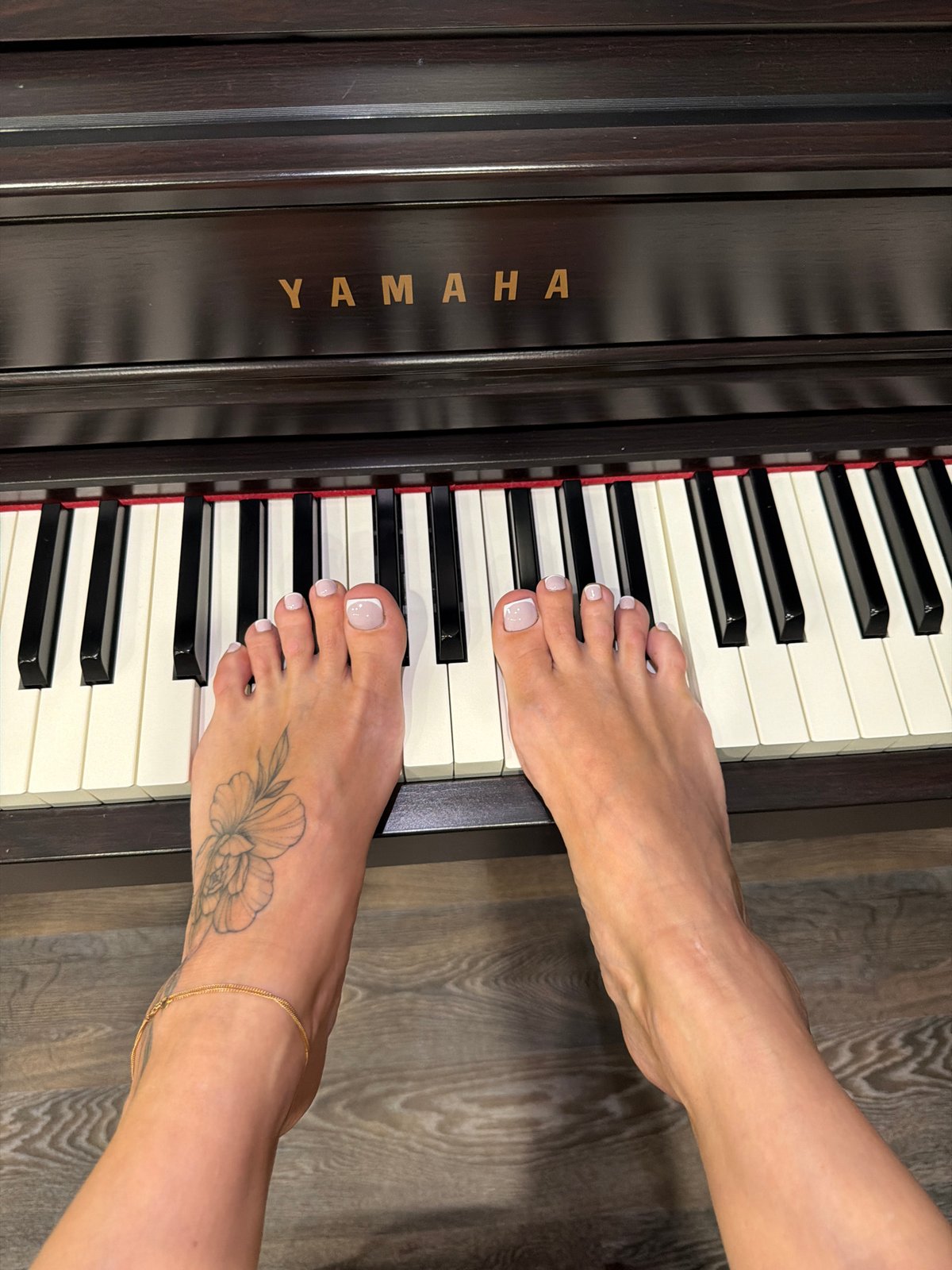 Bare feet with painted nails rest on piano keys