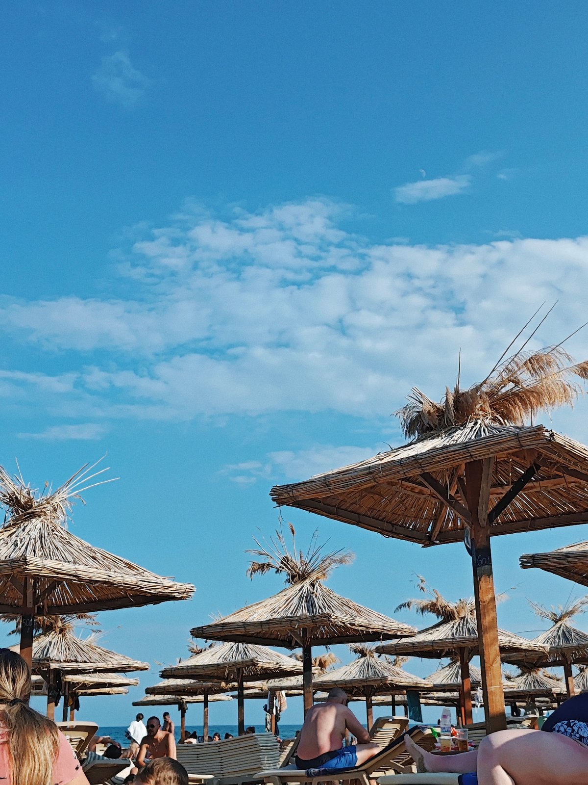 Crowded beach day under thatched umbrellas in the sun