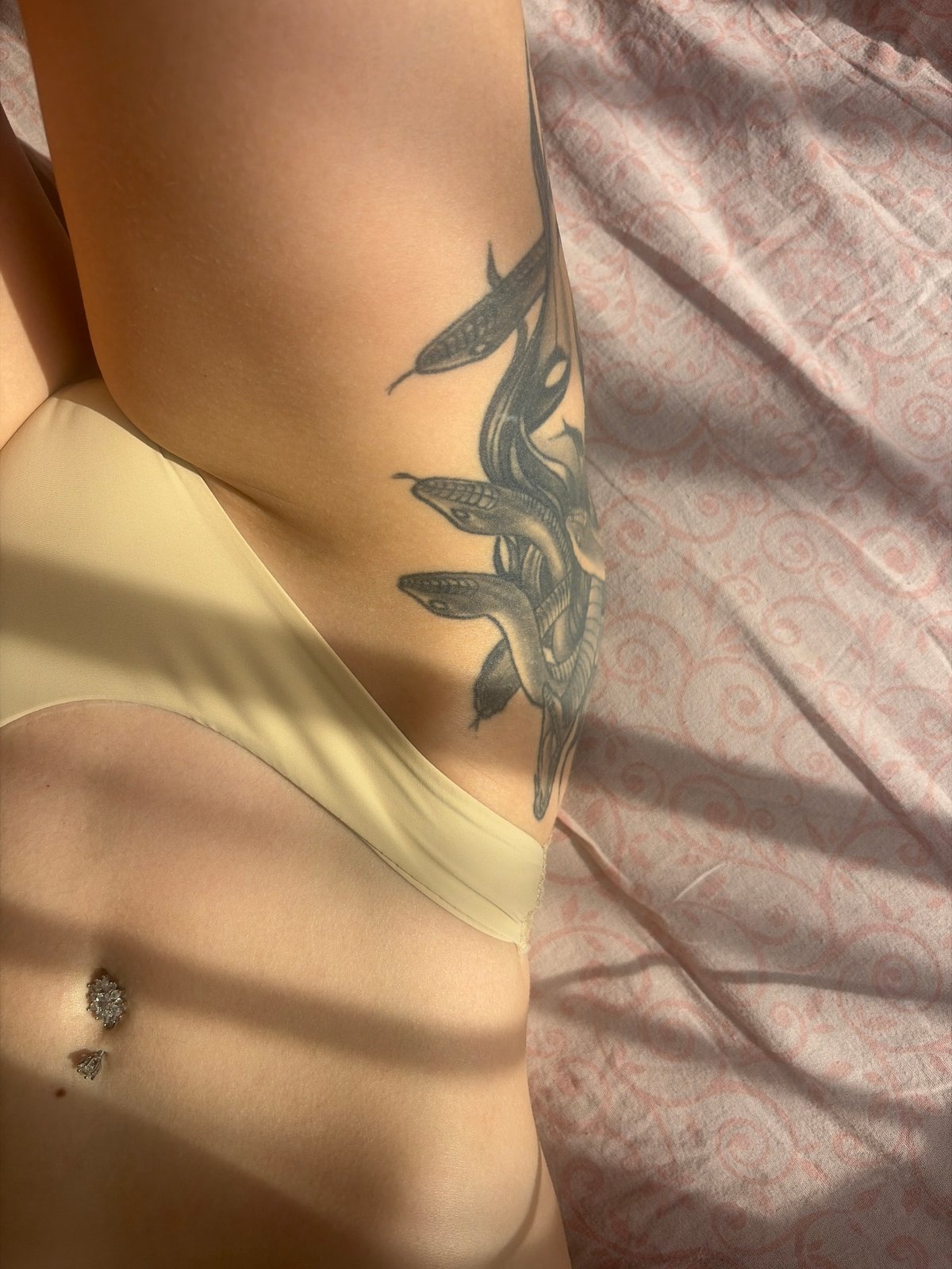 Person with snake tattoos photographed on pink fabric in Russia