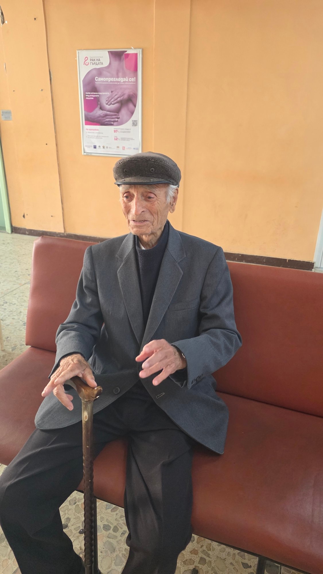Elderly man waits in Blagoevgrad room with cane