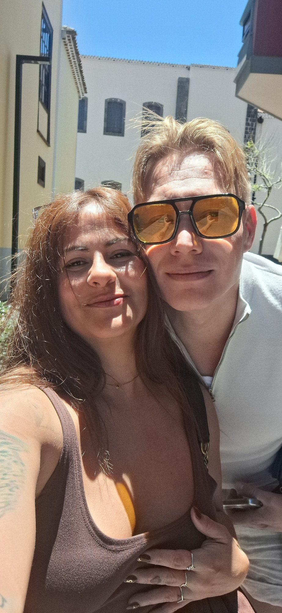 Two friends take selfies near bell tower on sunny day