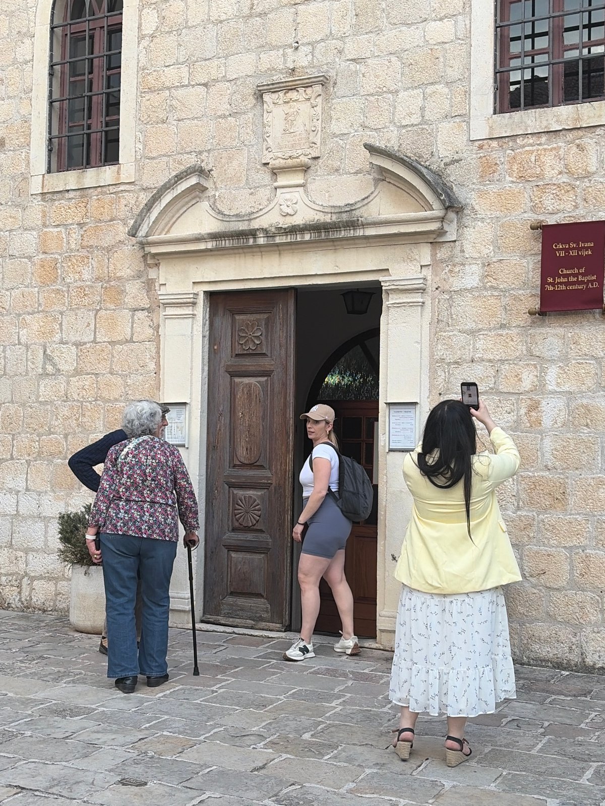Three women embrace near historic church in Budva, Montenegro