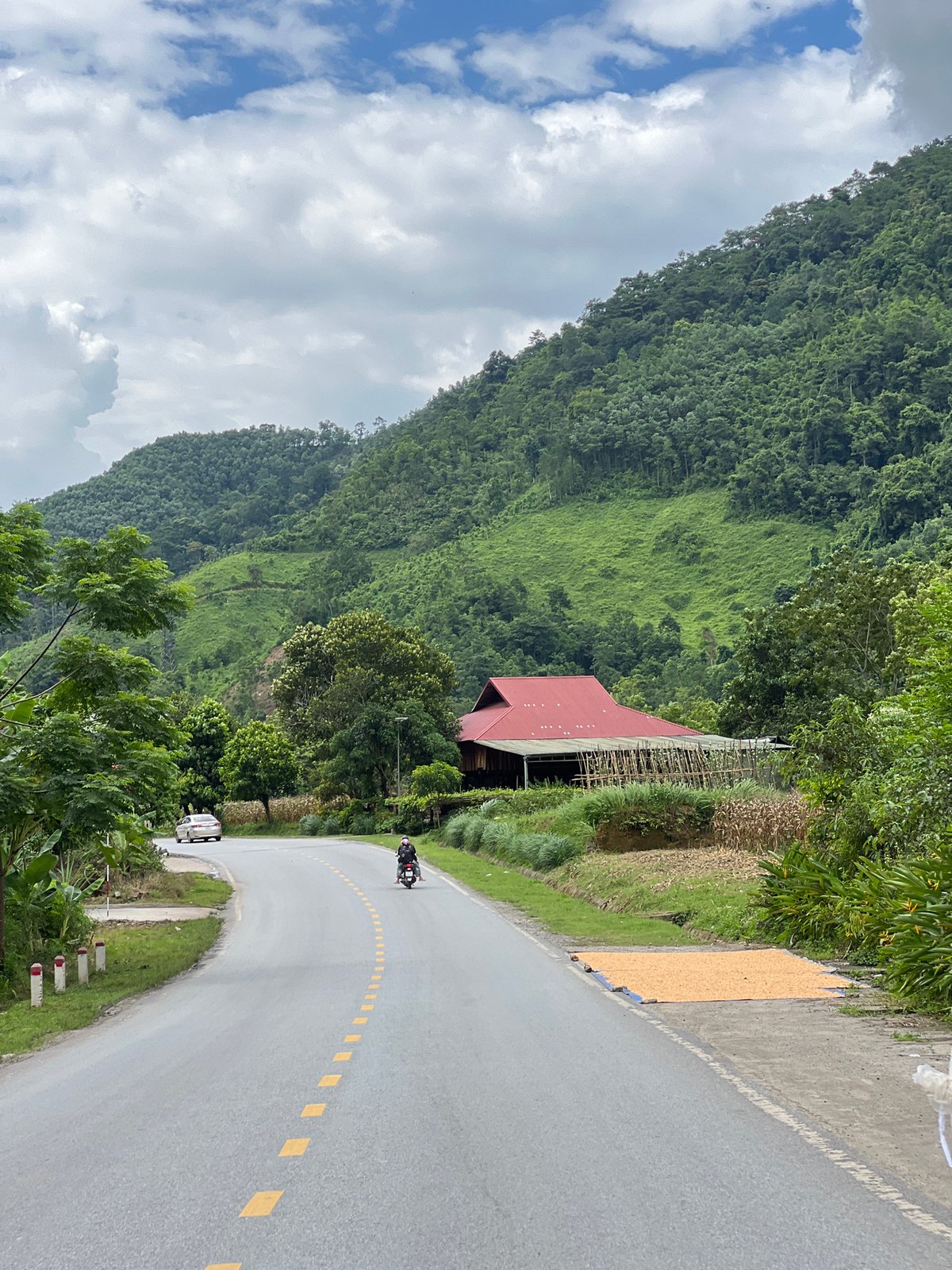 Winding mountain road past a red-roofed building in Thuận Hòa