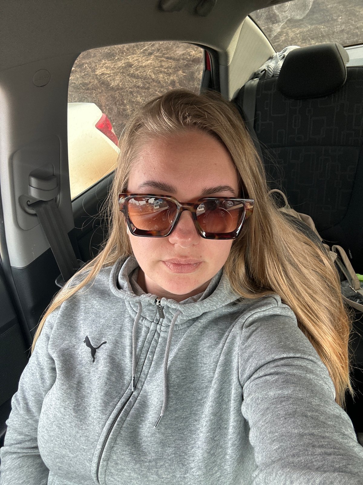 Woman in grey hoodie photographed inside car in Russia