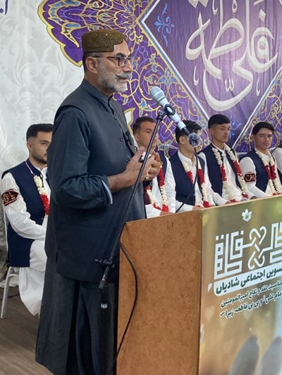Traditional-dressed speaker addresses audience in decorated Quetta venue
