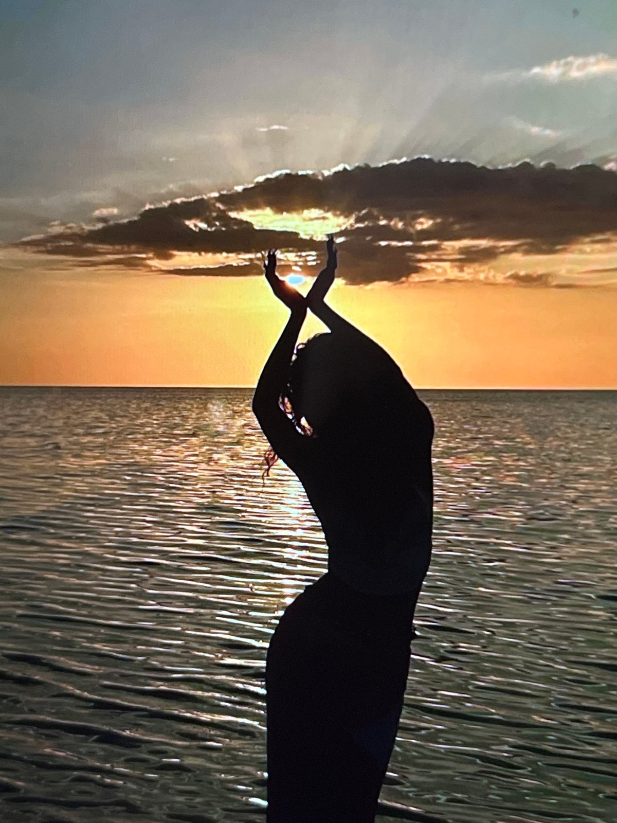 Flowing garment, raised arms, shallow water at sunset