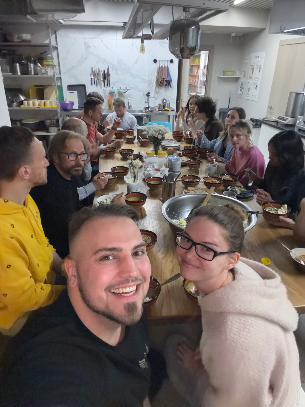 Dozen people share communal meal around wooden table in Moscow