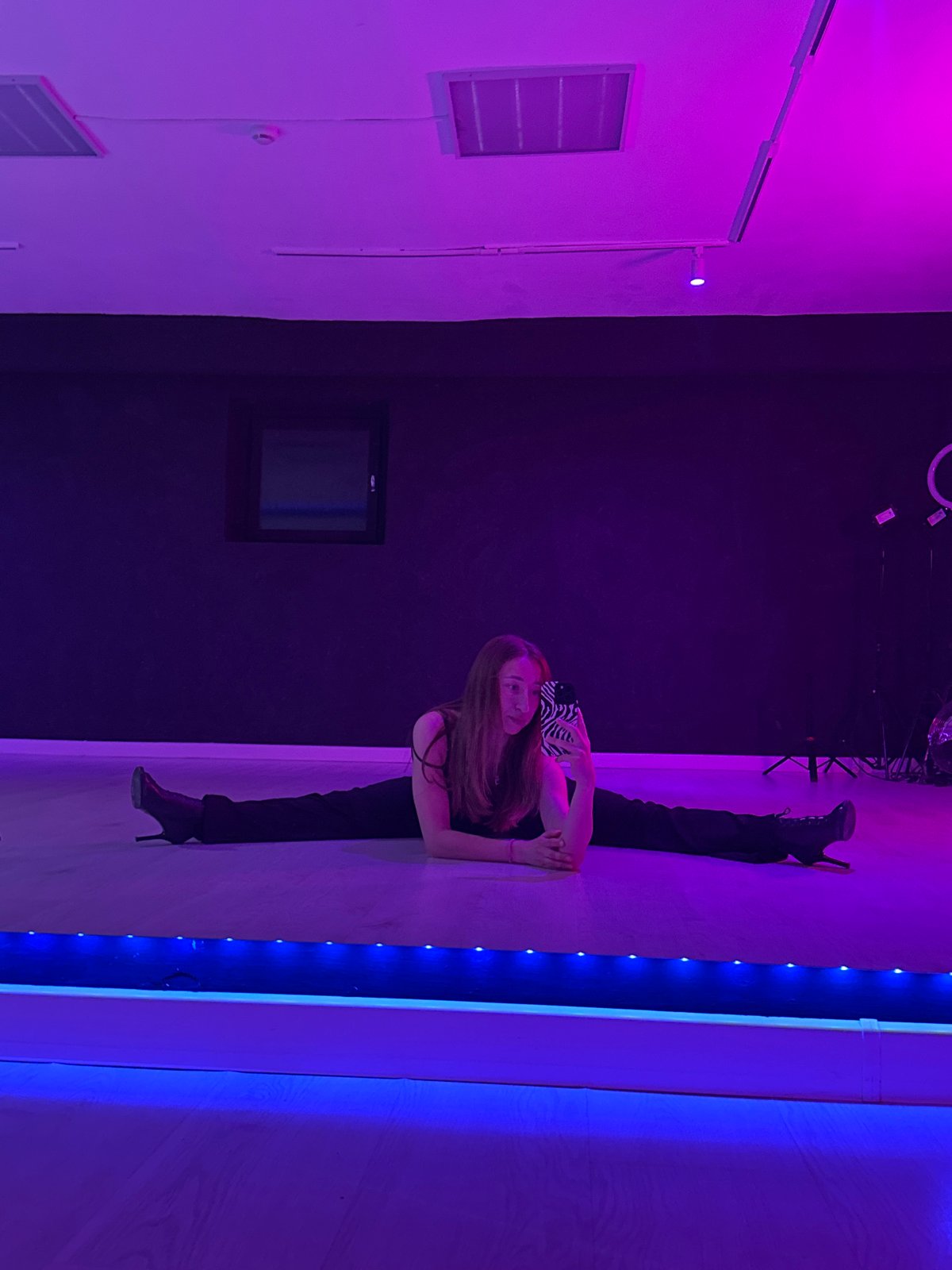 Woman takes selfies while stretching in neon-lit Chaikovsky room