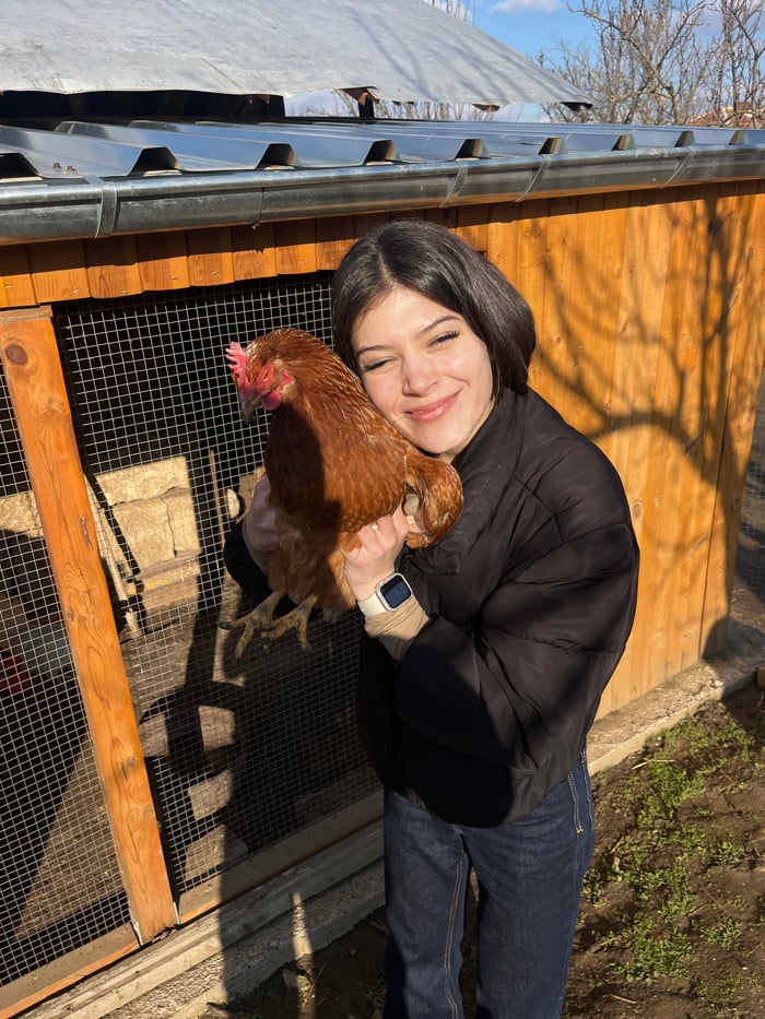 Young woman tends chickens in Bulgarian village yard