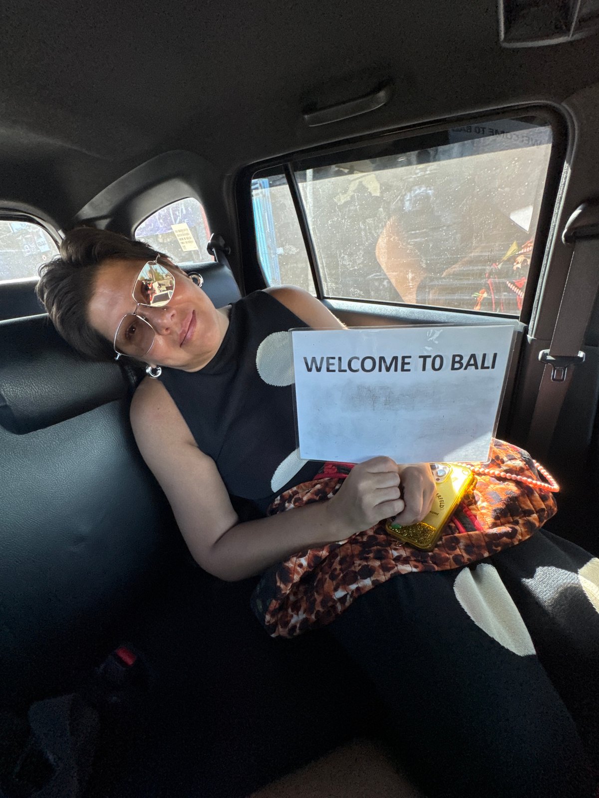 Tourist holds welcome sign in vehicle in Bali