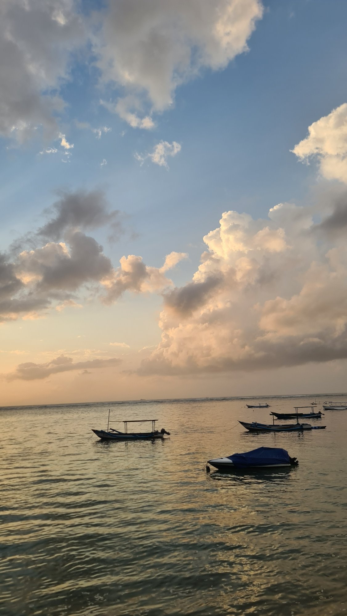 Seminyak Beach at dusk, boats, clouds, and golden light