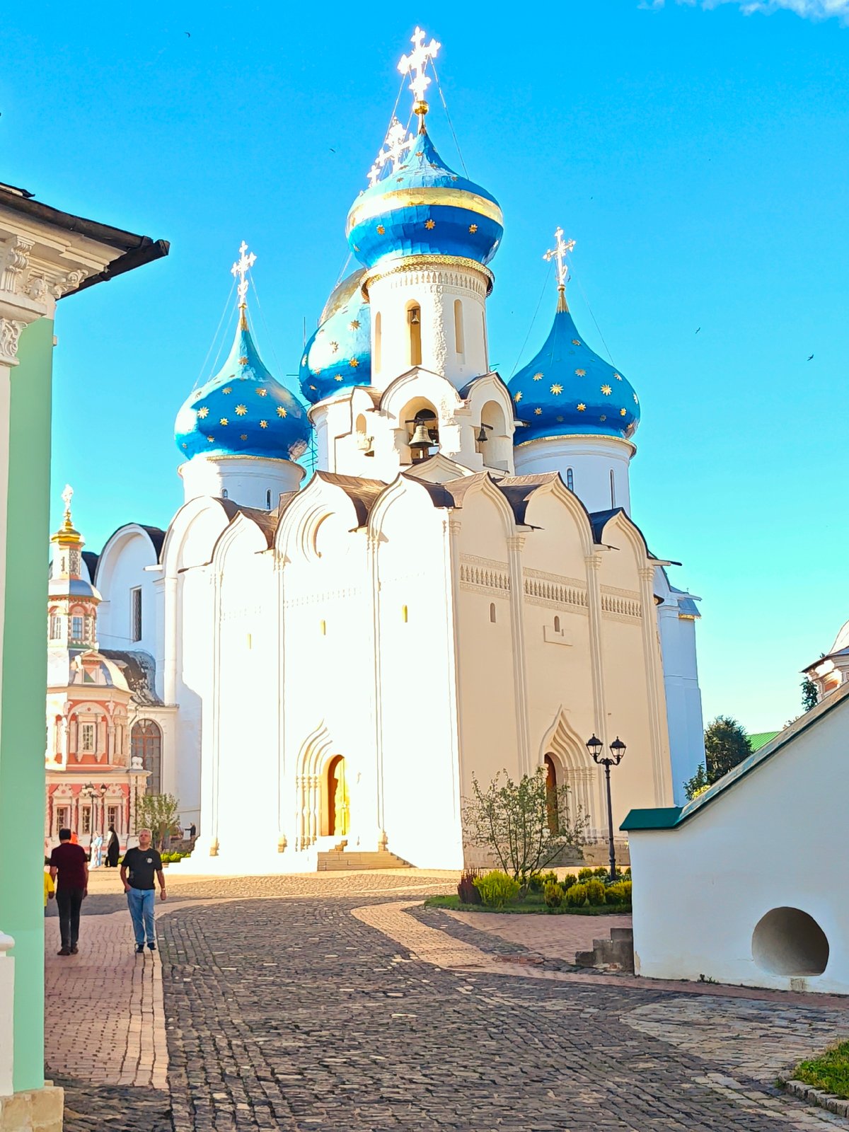 Afternoon at an Orthodox monastery complex, clergy and visitors in courtyard