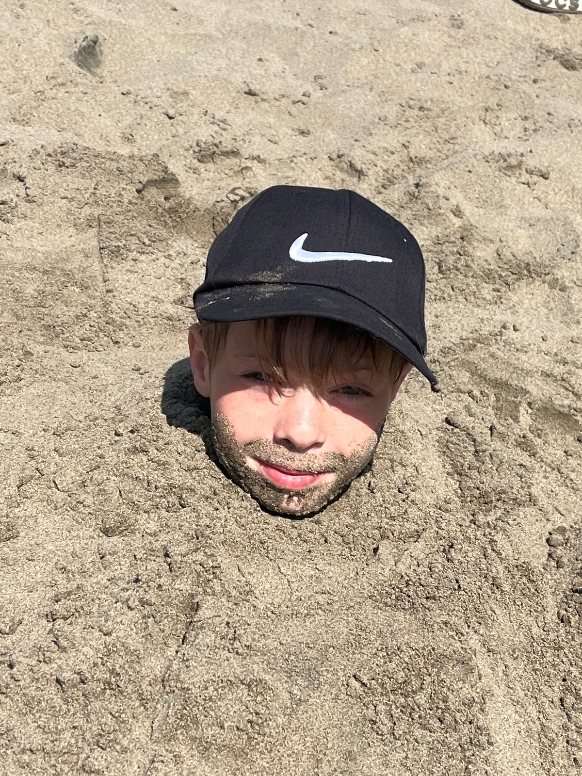 Kids bury a friend in sand on a Siberian beach