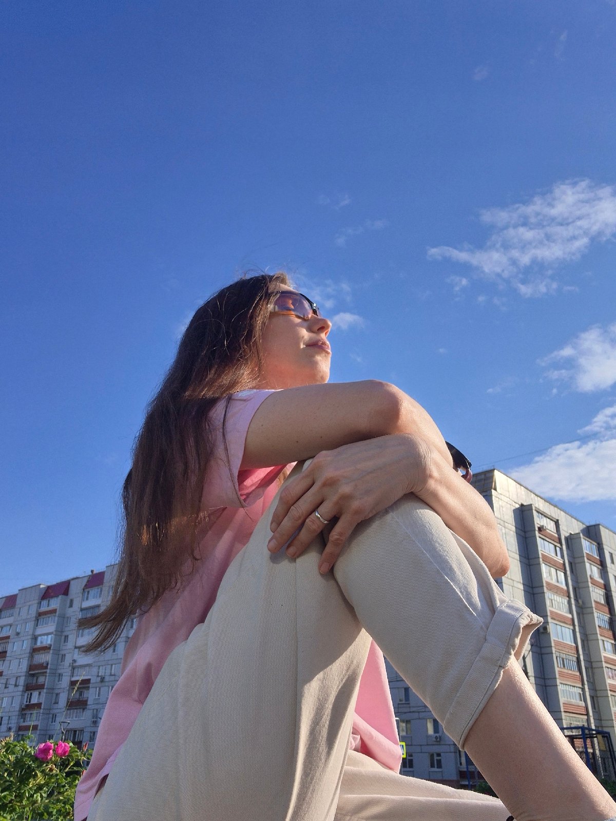 Woman in pink shirt sits outdoors in casual afternoon moment