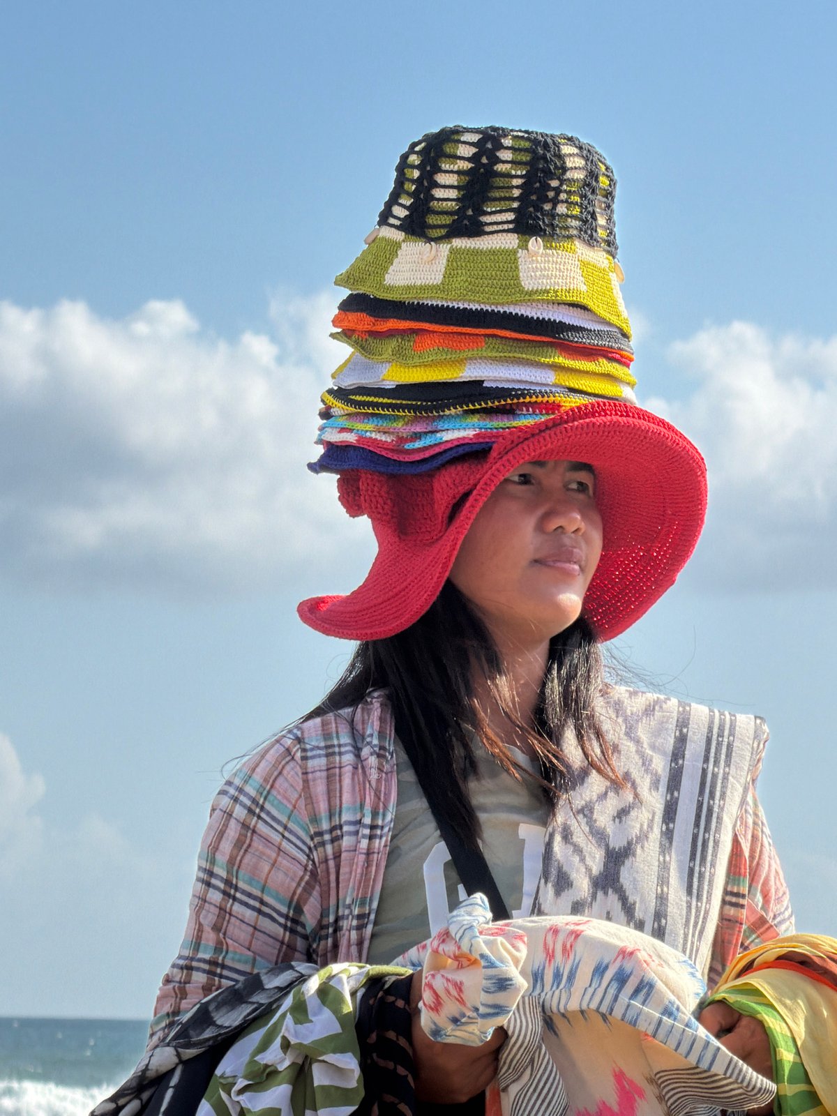 Stacked hats and fabric for sale on a North Kuta beach