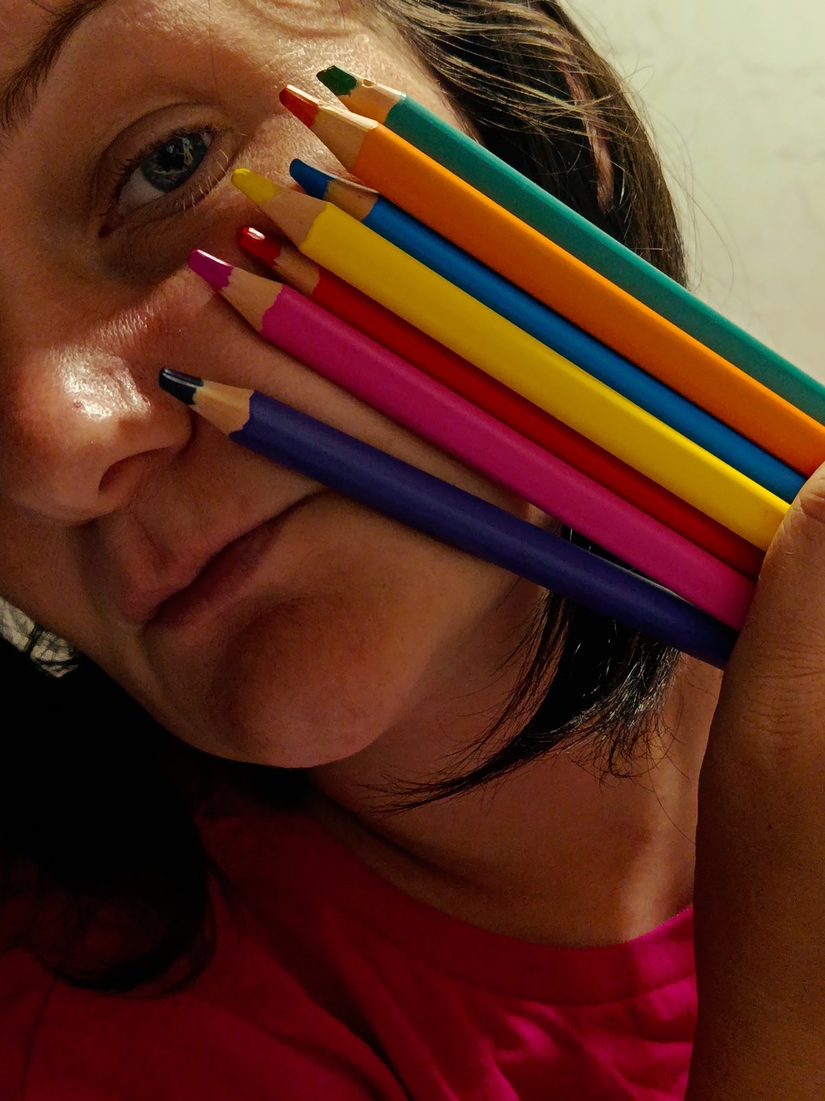 Person poses with colored pencils in indoor portrait