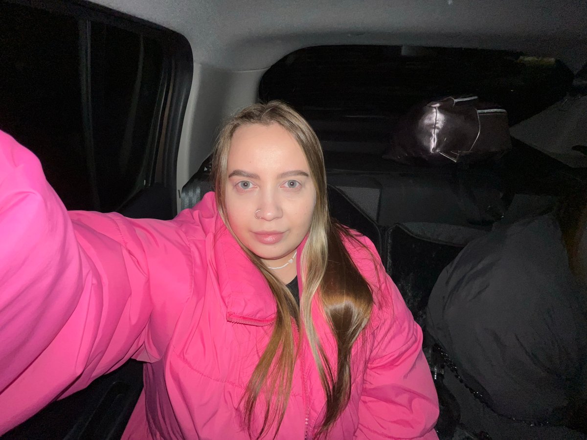 Woman in pink jacket photographed in vehicle back seat