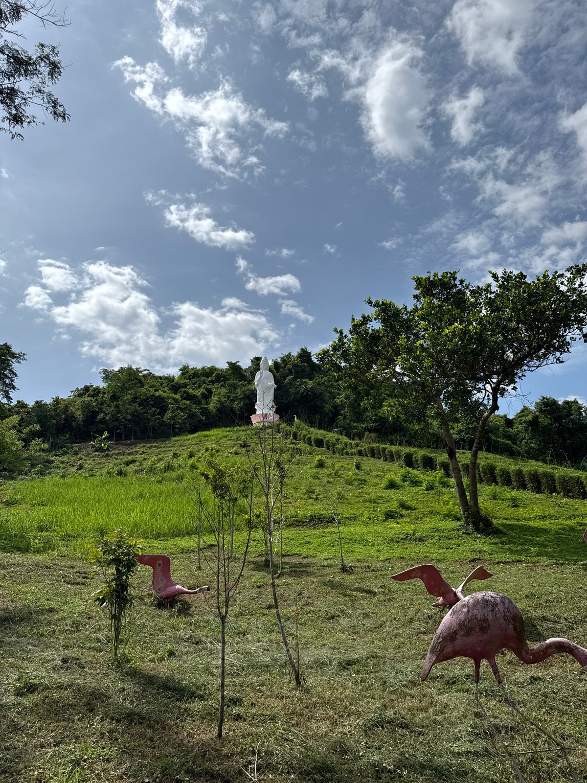 White deity statue overlooks green hills in Khanh Vinh