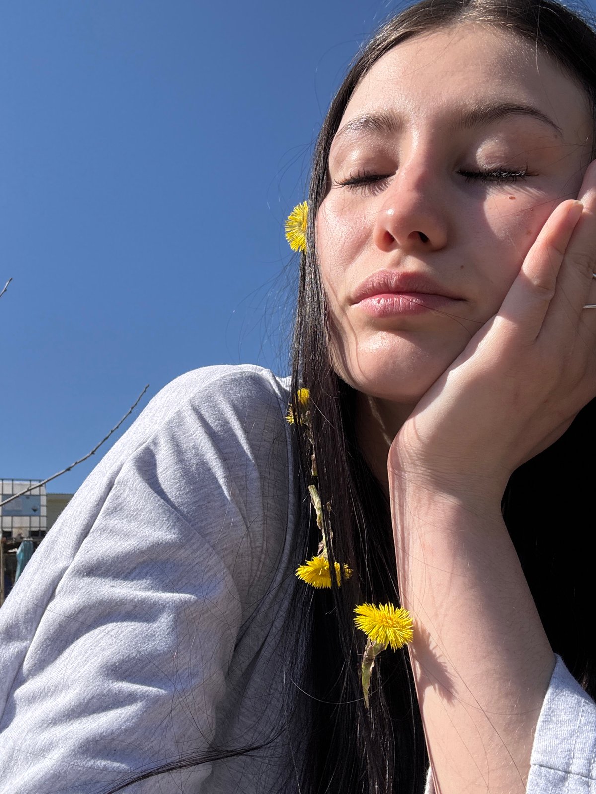 Woman documents sunny spring morning with flower selfies in Фоки