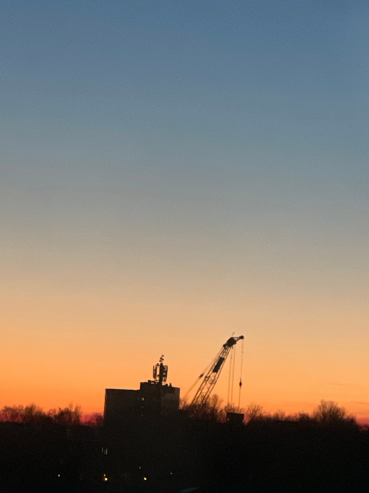 Construction crane silhouetted against sunset sky in Saint Petersburg