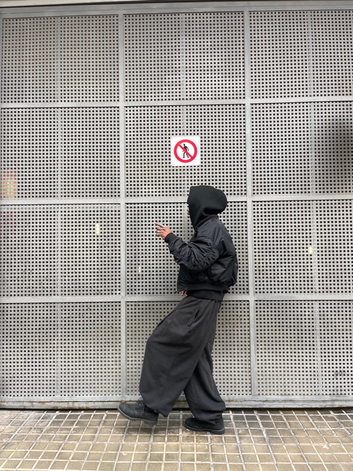 Person stands against metal wall in Barcelona street scene