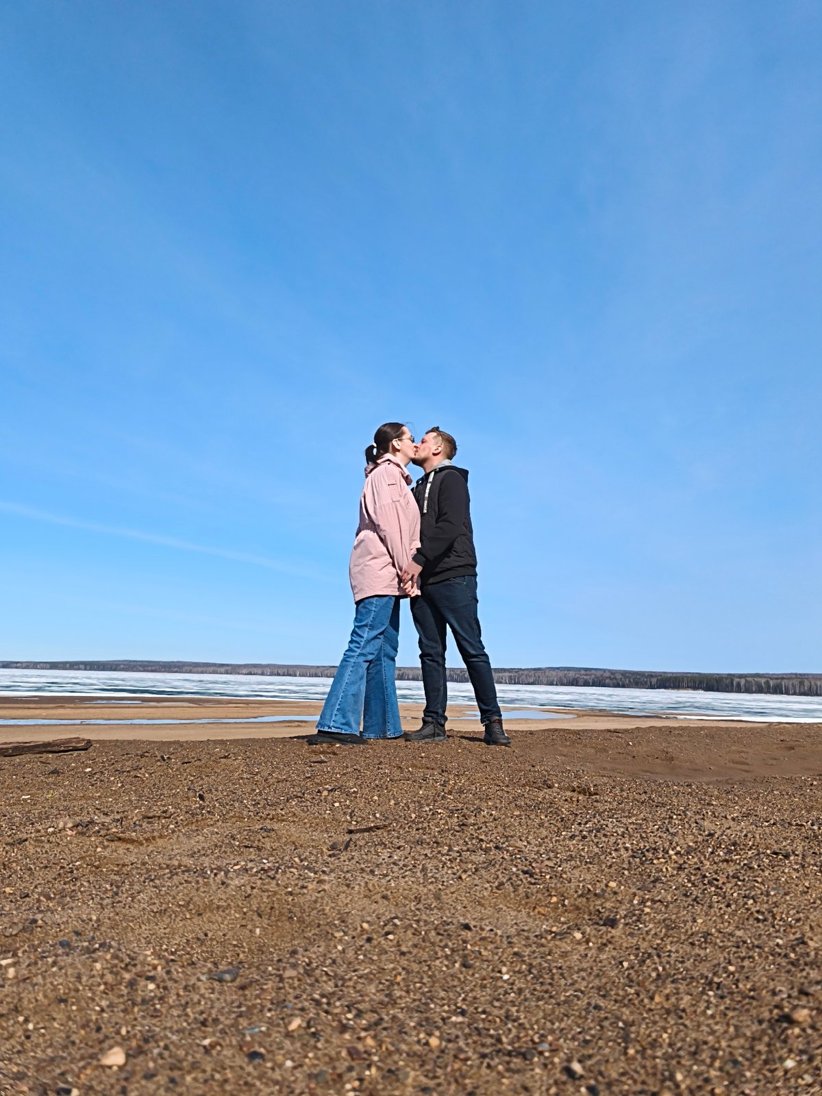 Couple shares romantic moment on beach, takes photos together