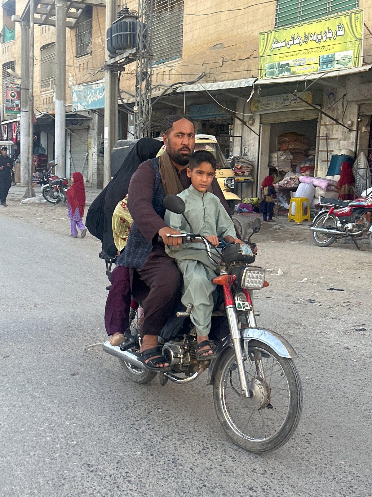 Red motorcycle moving through Quetta city streets