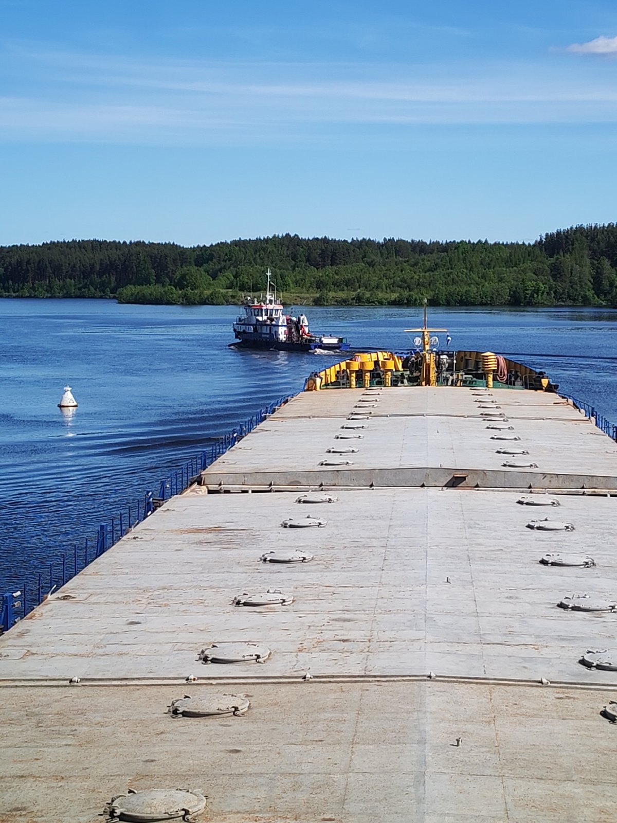 Tugboat guides barge through calm waterway under clear skies
