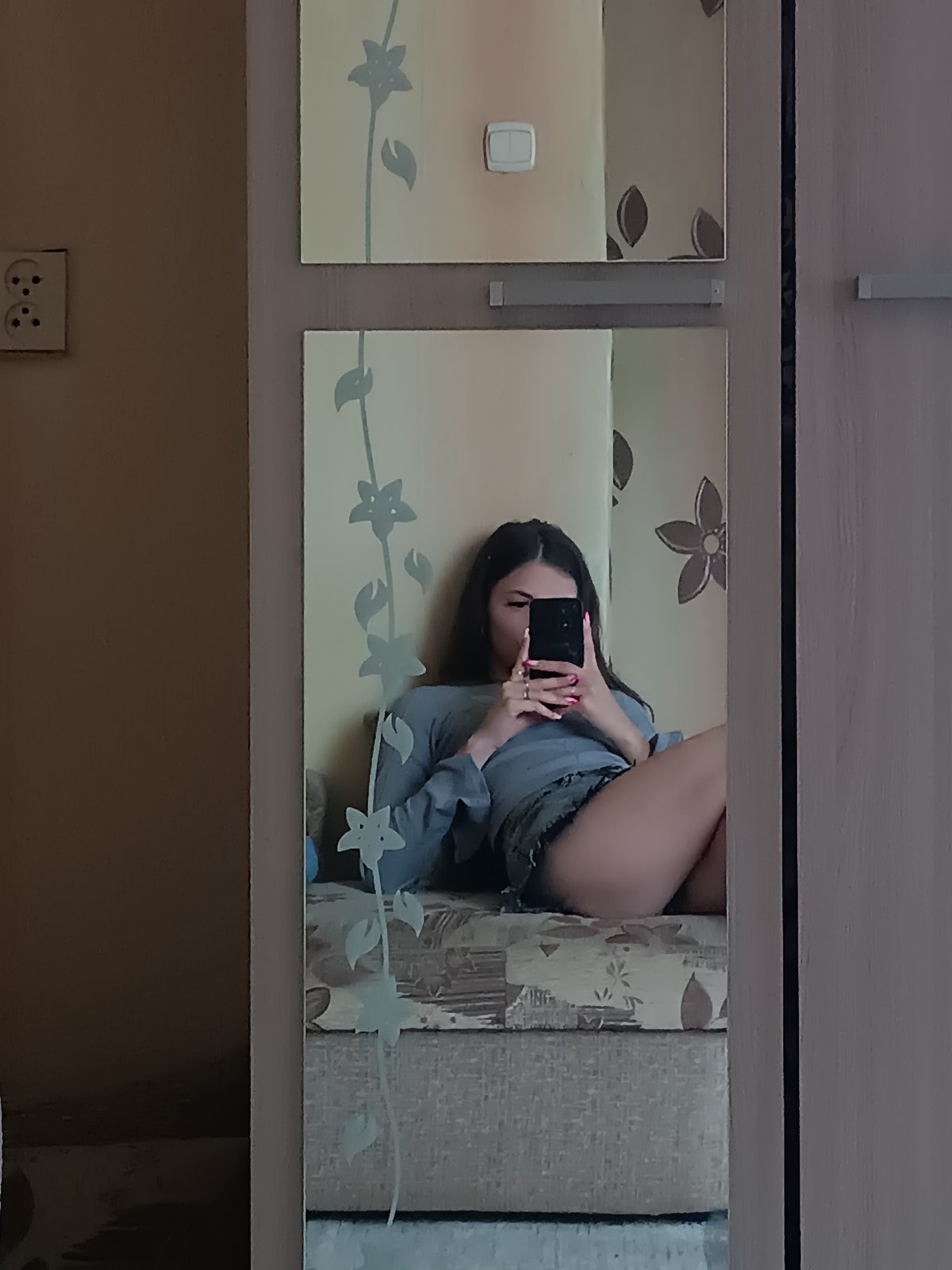 Mirror selfie on a patterned bench, casual outfit.