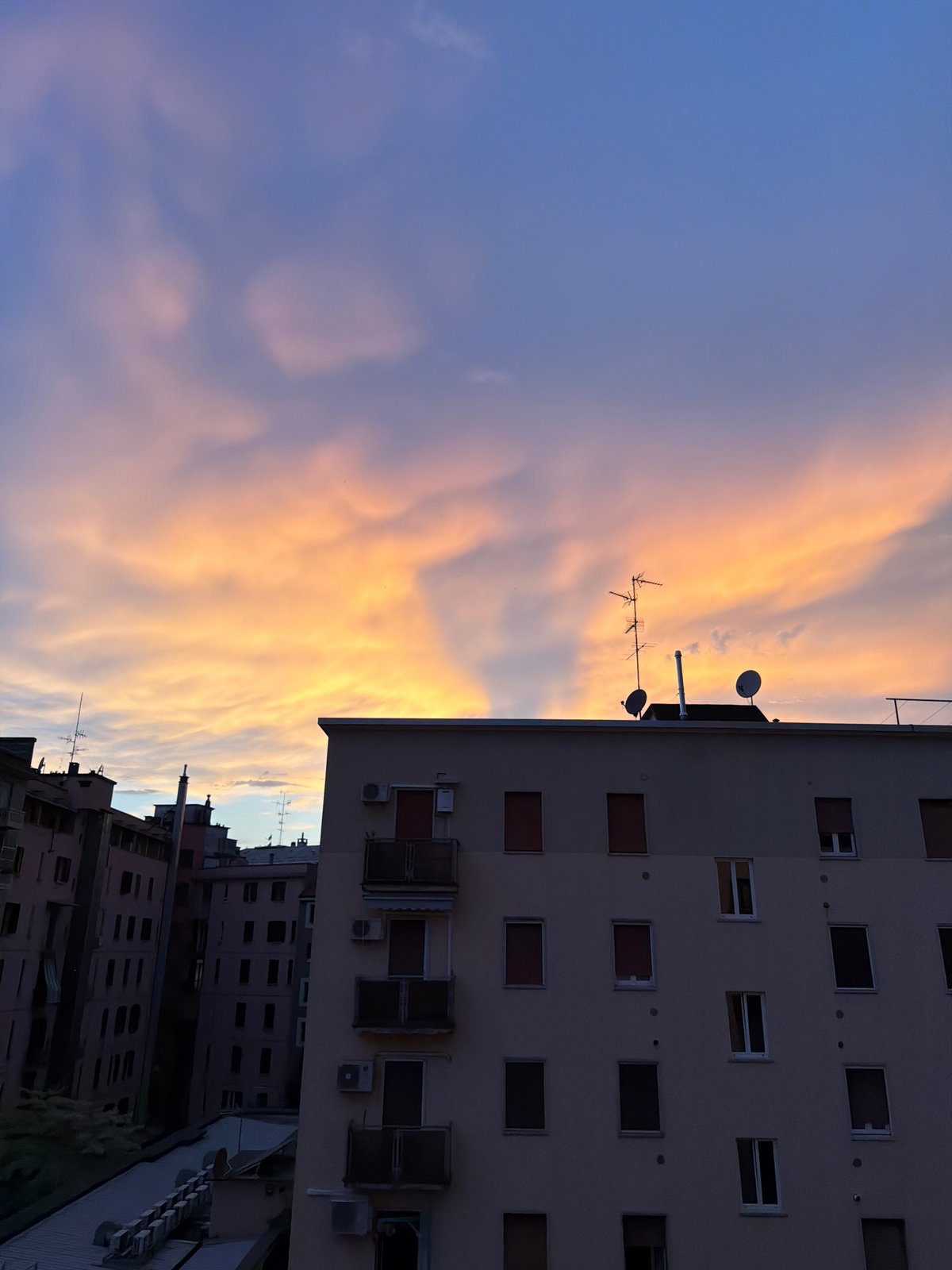 Milan's summer sunset, watched from the neighborhood rooftops and windows
