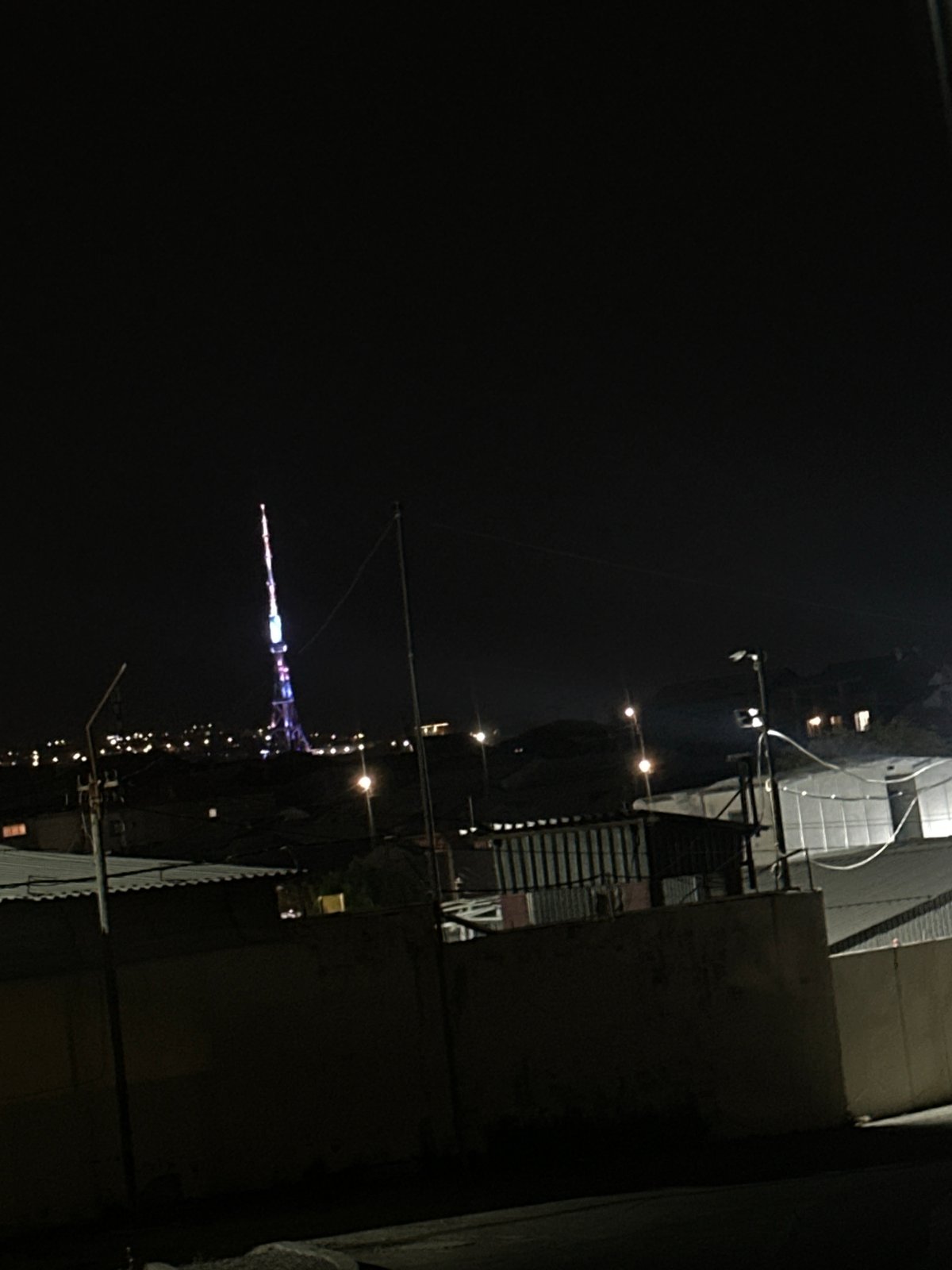 Nighttime urban documentation captures illuminated tower, vehicles, buildings