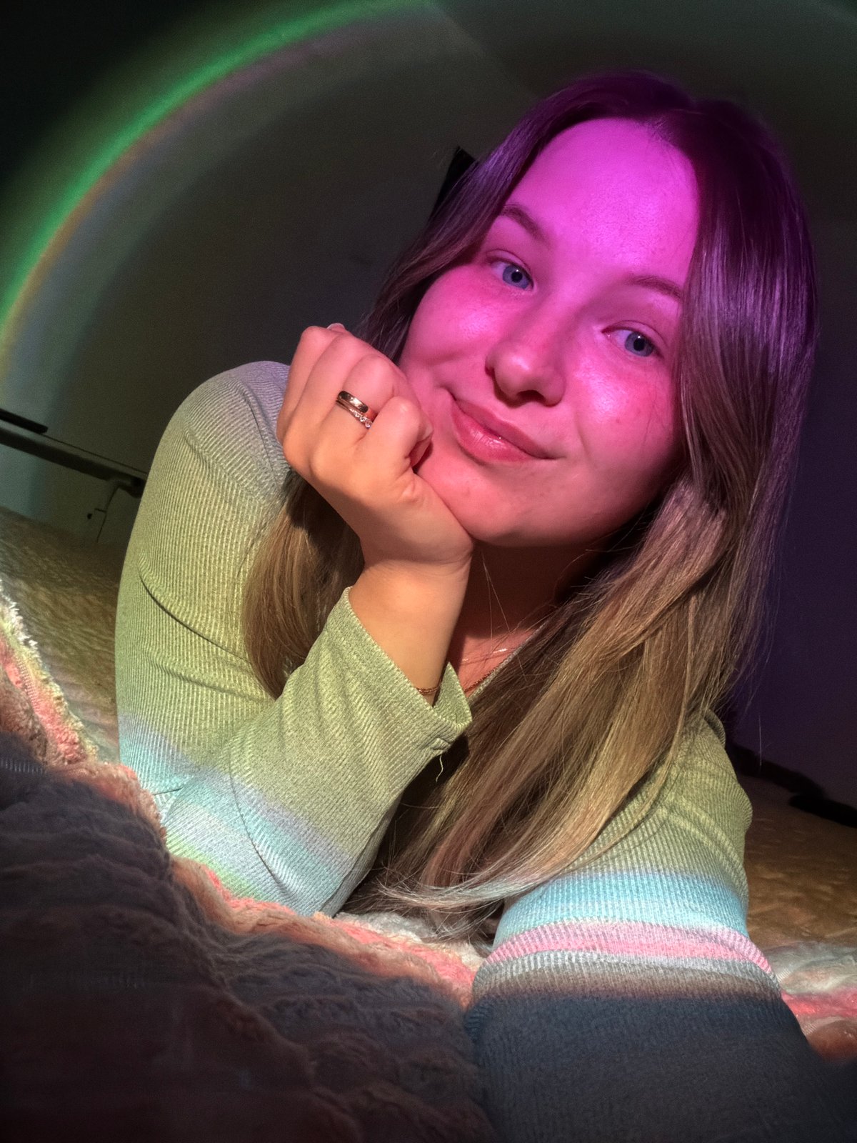 Woman rests on bed with rainbow light in Chaikovsky