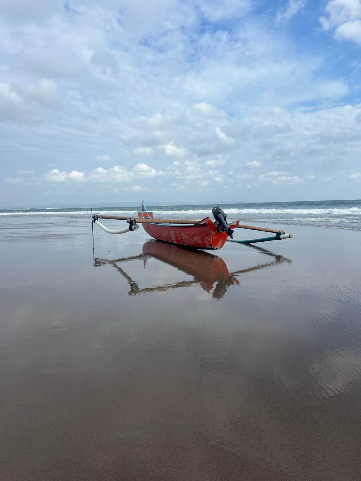 Red boat resting on the beach in North Kuta, Bali
